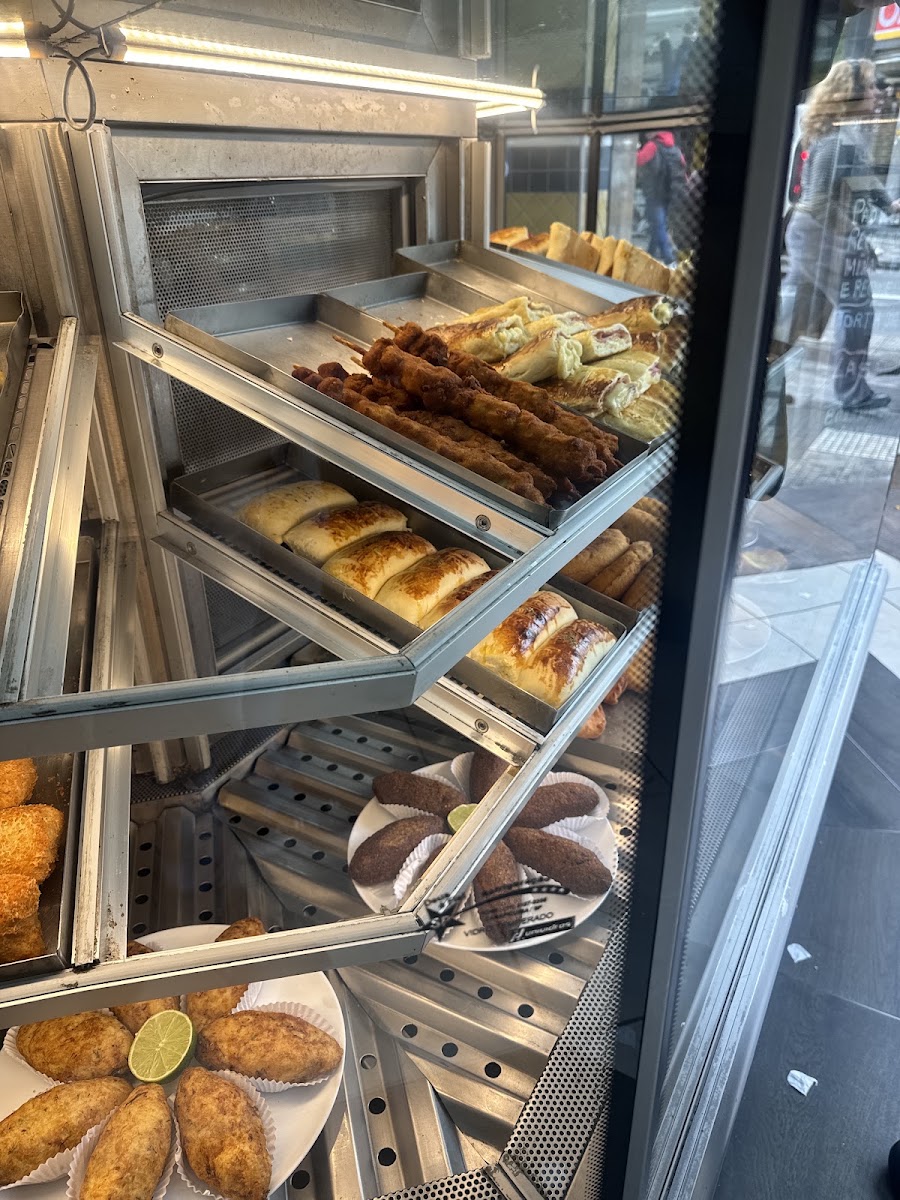 Vitrine com salgados fritos, coxinhas e esfihas, vista da rua